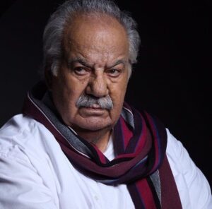 ناصر ملک مطیعی با پیراهن سفید و شال راه راه زرشکی