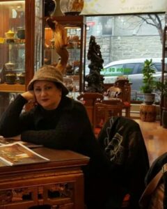 عکسی از مریم امیرجلالی با لباس مشکی و کلاه در یک کافه