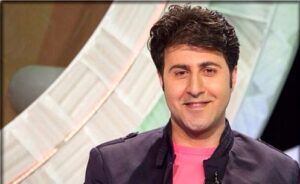 هومن حاجی عبداللهی با کن مشکی و تیشرت قرمز در یک برنامه تلویزیونی