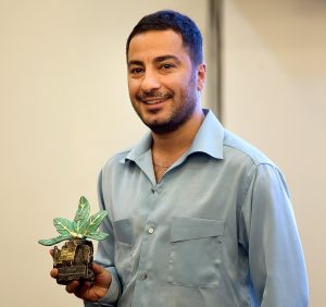 نوید محمدزاده با پیراهن طوسی و یک گل در دستش